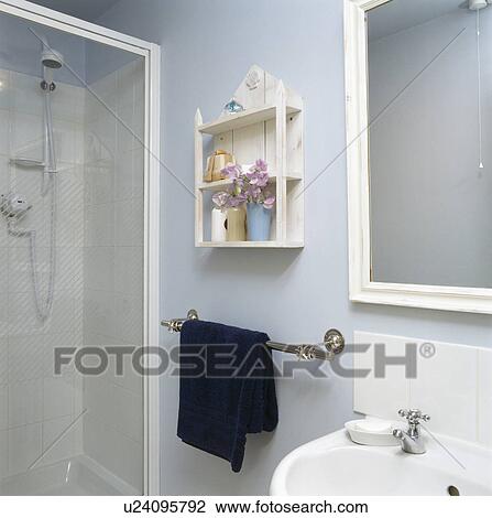 Stock Image - White shelves and glass shower cabinet in small pastel blue bathroom. Fotosearch