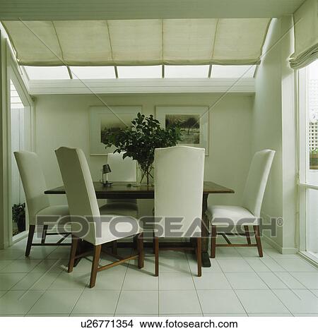 White upholstered chairs in modern white dining room with white ceiling blind View Large Photo Image Picture - White upholstered chairs in modern white dining room with white ceiling blind. Fotosearch