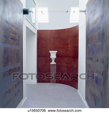 White urn on plinth in front of curved modern panelled wall in hall corridor with large abstract paintings View Large Photo Image Stock Photograph - White urn on plinth in front of curved modern panelled wall in hall corridor with large abstract paintings. Fotosearch