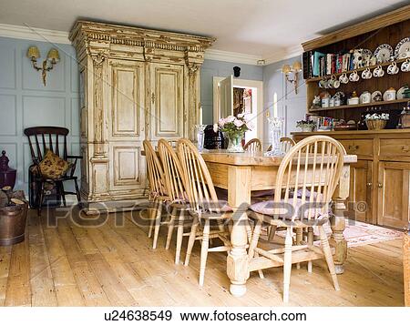 Windsor Chairs And Wooden Table In Pale Blue Country Dining Room With Large Ornate Cream Cupboard And Pine Dresser Stock Photo U24638549 Fotosearch