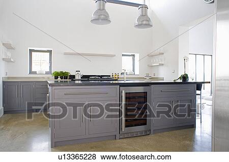 Wine cooler in grey fitted island unit below metal fisherman's lighting in modern white ktichen View Large Photo Image Stock Photo - Wine cooler in grey fitted island unit below metal fisherman's lighting in modern white ktichen . Fotosearch