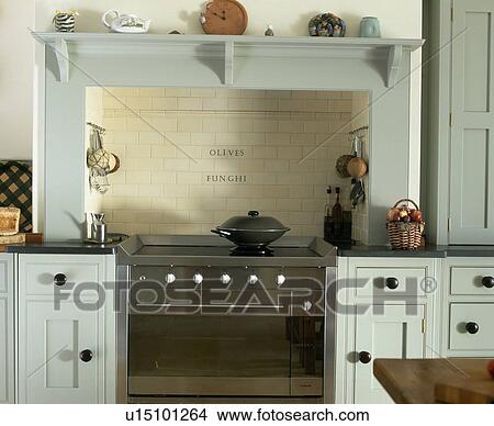 Picture - Wok on stainless steel oven in kitchen with pastel blue fitted units. Fotosearch