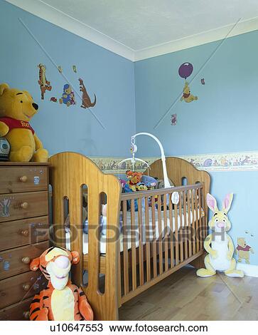 Stock Image - Wooden cot in baby's pastel blue nursery bedroom. Fotosearch