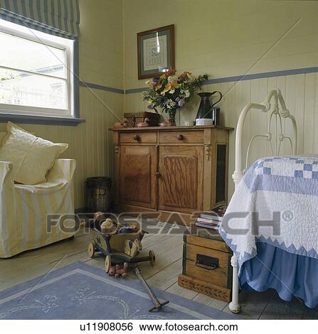 Wooden cupboard and yellow striped chair in child's Shaker-style bedroom  View Large Photo Image Stock Photograph - Wooden cupboard and yellow striped chair in child's Shaker-style bedroom . Fotosearch