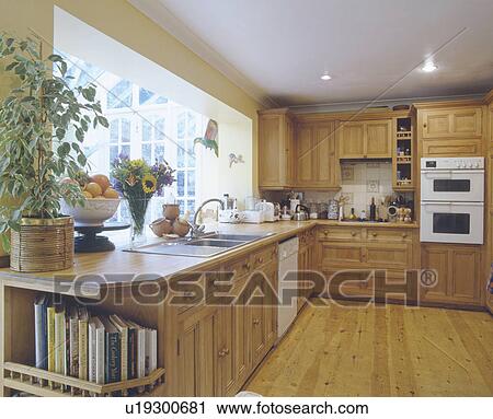 Stock Image - Wooden flooring and white oven in fitted wooden kitchen. Fotosearch