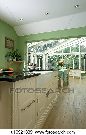 Stock Photo - Wooden flooring in green kitchen with large conservatory dining room extension. Fotosearch