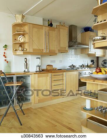 Stock Image - Wooden flooring in modern kitchen with pale wood fitted units. Fotosearch