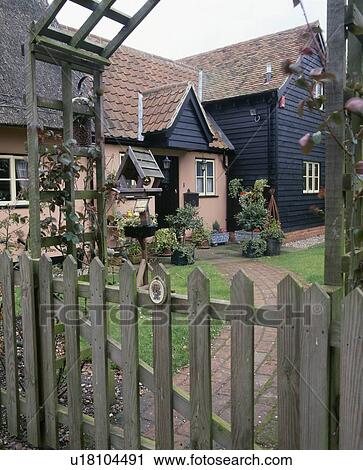 Stock Image - Wooden gate to small front garden with paved path to country cottage. Fotosearch