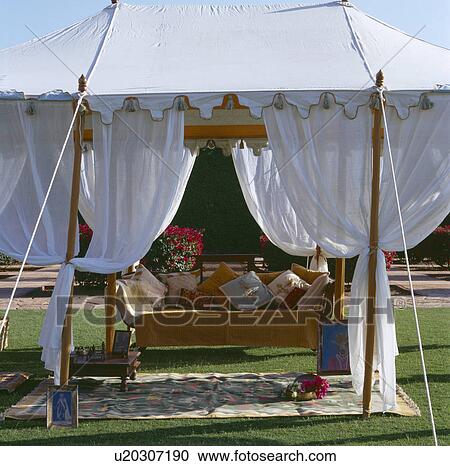 Wooden settle piled with cushions in traditional white Rajastani tent with white drapes View Large Photo Image Stock Image - Wooden settle piled with cushions in traditional white Rajastani tent with white drapes. Fotosearch