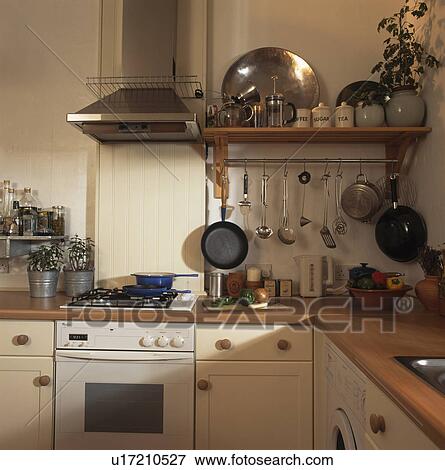 Stock Photo - Wooden shelving and stainless steel extractor in small modern kitchen. Fotosearch