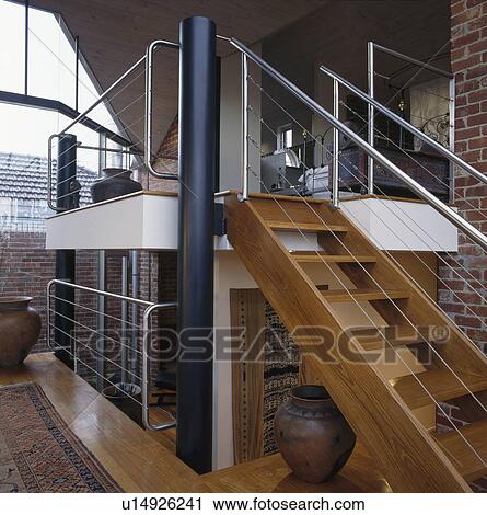 Stock Image - Wooden staircase to mezzanine floor in large openplan hall. Fotosearch