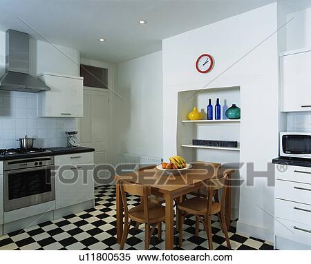 Stock Photography - Wooden table and chair in modern kitchen with black+white chequerboard floor. Fotosearch