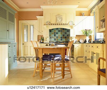 Stock Image - Wooden table and chairs in country kitchen painted in Farrow+Ball paint. Fotosearch