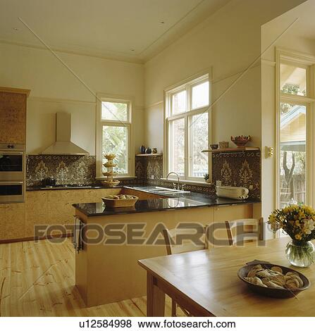 Wooden table and chairs in open-plan modern dining room and kitchen View Large Photo Image Stock Photo - Wooden table and chairs in open-plan modern dining room and kitchen. Fotosearch