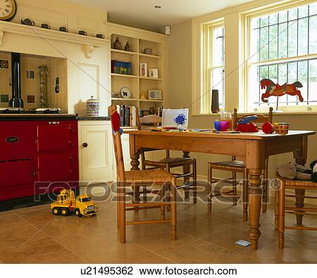 Wooden table and chairs in traditional family kitchen with red Aga oven View Large Photo Image Stock Image - Wooden table and chairs in traditional family kitchen with red Aga oven . Fotosearch