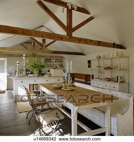 Wooden Table And Painted White Settle In White Barn Conversion