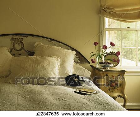 Antique bedside table beside bed with white linen in small white bedroom View Large Photo Image Stock Photography - Antique bedside table beside bed with white linen in small white bedroom. Fotosearch