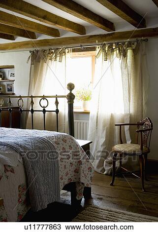 Antique chair and brass bed in beamed cottage bedroom View Large Photo Image Stock Image - Antique chair and brass bed in beamed cottage bedroom. Fotosearch