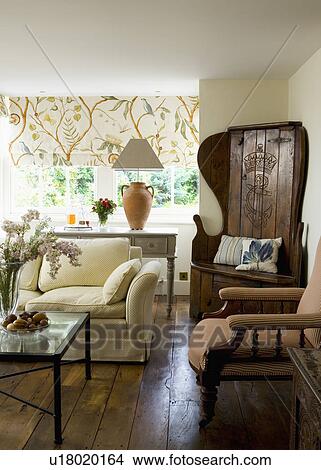 Picture - Antique chair-cum-bacon cupboard in corner of cream country living room with wooden floor. Fotosearch