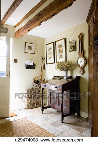 Stock Photo - Barometer on wall above antique desk in cream country hall with beamed ceiling. Fotosearch