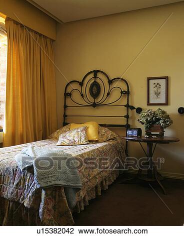 Bed with ornate metal headboard in Spanish bedroom with cream curtains View Large Photo Image Stock Image - Bed with ornate metal headboard in Spanish bedroom with cream curtains. Fotosearch