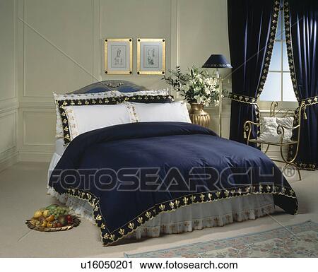 Bed With White Pillows And Gold Trimmed Dark Blue Throw With