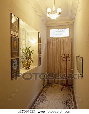 Stock Image - Bentwood coatstand and mosaic tiled floor in narrow hall with curtain on door. Fotosearch