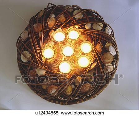 Stock Photography - Birdseye view of lighted candles in wicker wreath decorated with seashells. Fotosearch
