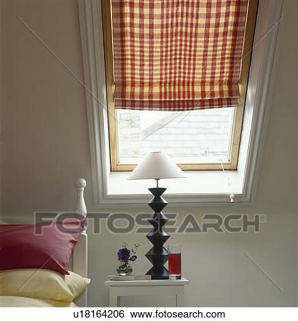 Black lamp with white shade below Velux window with red & white checked blind in loft conversion bedroom View Large Photo Image Stock Photograph - Black lamp with white shade below Velux window with red & white checked blind in loft conversion bedroom. Fotosearch