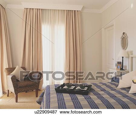 Blue checked bedlinen on bed in modern bedroom with beige curtains View Large Photo Image Stock Photo - Blue checked bedlinen on bed in modern bedroom with beige curtains. Fotosearch