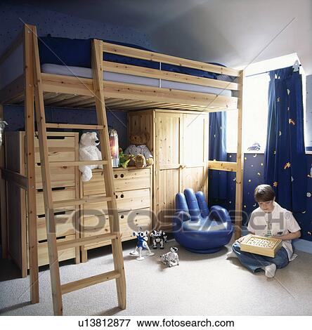 Stock Photo - Blue hand shaped armchair and ladder to bunk bed with storage cupboards below in childrens bedroom. Fotosearch