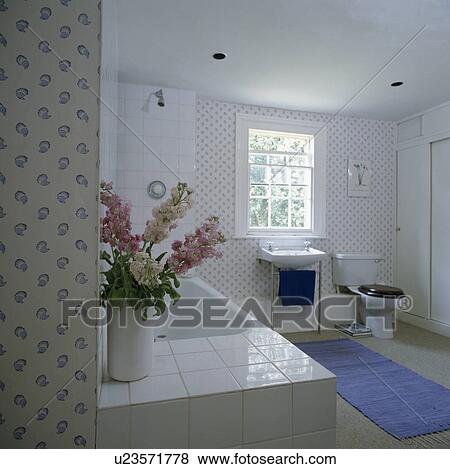 Stock Photo - Blue rug in white country bathroom with blue and white floral tiles. Fotosearch