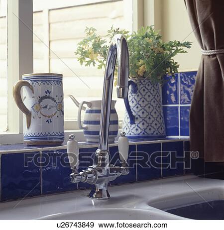 Blue & white jugs on blue tiled windowsill above chrome sink tap View Large Photo Image Stock Photo - Blue & white jugs on blue tiled windowsill above chrome sink tap. Fotosearch