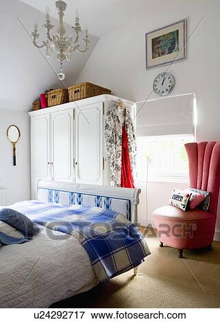Blue+white checked throw on French bed in contemporary bedroom with white wardrobe and upholstered red chair View Large Photo Image Stock Photo - Blue+white checked throw on French bed in contemporary bedroom with white wardrobe and upholstered red chair. Fotosearch