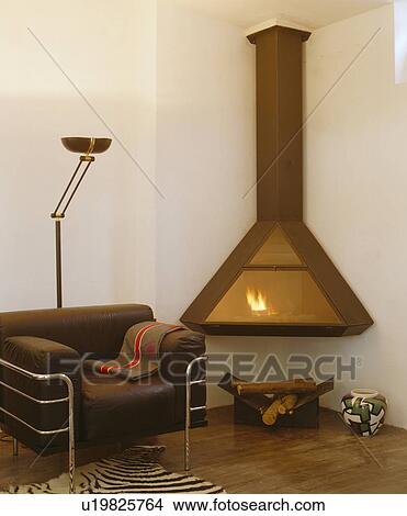 Brown leather+chrome armchair beside corner wall-mounted modern fireplace View Large Photo Image Picture - Brown leather+chrome armchair beside corner wall-mounted modern fireplace. Fotosearch