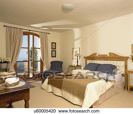 Stock Image - Brown mohair throw on bed in apartment bedroom with patio doors to balcony. Fotosearch