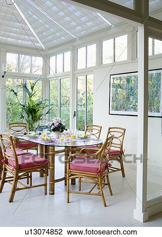 Cane chairs with red cushions in Marston + Langinger conservatory dining room with white ceramic floor tiles View Large Photo Image Stock Image - Cane chairs with red cushions in Marston + Langinger conservatory dining room with white ceramic floor tiles. Fotosearch