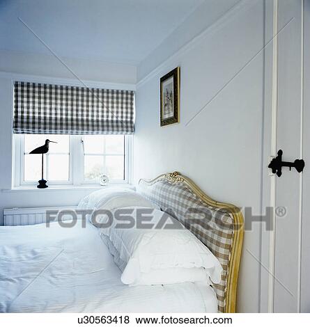 Checked blind on window in small white bedroom with white linen on bed View Large Photo Image Stock Photo - Checked blind on window in small white bedroom with white linen on bed. Fotosearch