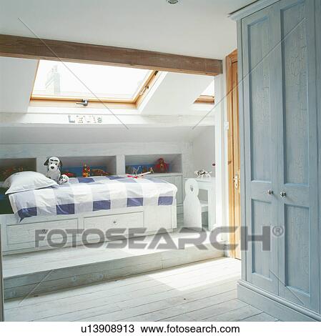 Stock Image - Child's modern loft conversion bedroom with underbed storage and checked bedlinen. Fotosearch