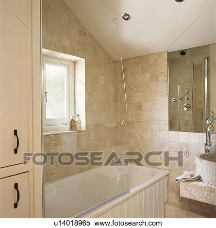 Clear perspex shower screen on bath in modern bathroom with stone tiled walls View Large Photo Image Stock Photography - Clear perspex shower screen on bath in modern bathroom with stone tiled walls. Fotosearch