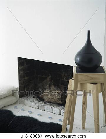 Close-up of black vase on modern wooden stool beside fireplace View Large Photo Image Stock Photo - Close-up of black vase on modern wooden stool beside fireplace. Fotosearch