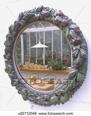 Close-up of ceramic-framed circular mirror reflecting conservatory dining room View Large Photo Image Stock Photo - Close-up of ceramic-framed circular mirror reflecting conservatory dining room. Fotosearch