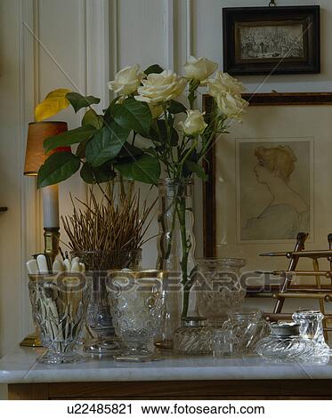 Stock Image - Close-up of cut-glass collection with cream roses in glass vase. Fotosearch