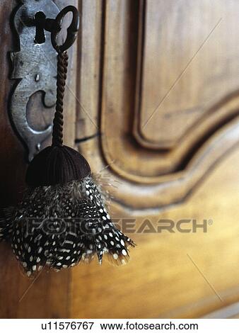 Stock Photo - Close-up of feather tassel on key in old cupboard. Fotosearch