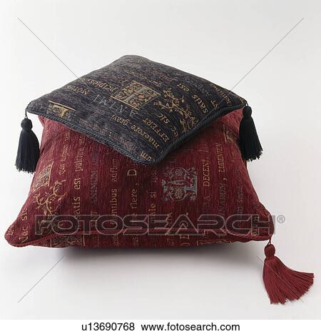 Stock Photo - Close-up of graffiti-patterned brown and red velvet cushions with tassels. Fotosearch