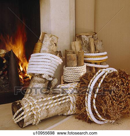 Close-up of logs bound with string in front of fireplace with lighted fire View Large Photo Image Stock Photo - Close-up of logs bound with string in front of fireplace with lighted fire. Fotosearch