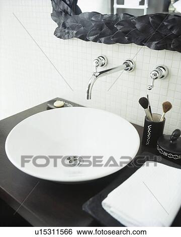 Stock Photograph - Close-up of modern white bowl basin on black vanity unit. Fotosearch