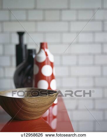 Stock Photograph - Close-up of modern wooden bowl and red spotted vase. Fotosearch