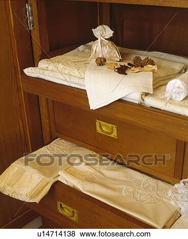 Stock Photo - Close-up of monogrammed yellow silk sheets in antique chest-of-drawers. Fotosearch