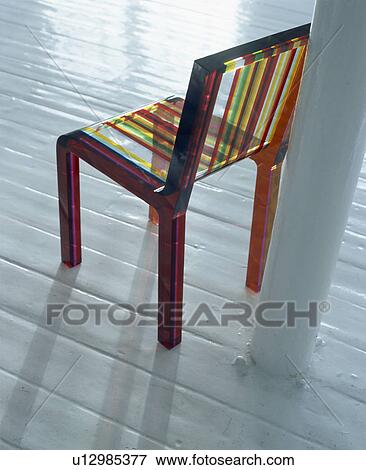 Close-up of multi-coloured striped perspex dining chair on white wooden flooring View Large Photo Image Stock Photo - Close-up of multi-coloured striped perspex dining chair on white wooden flooring. Fotosearch
